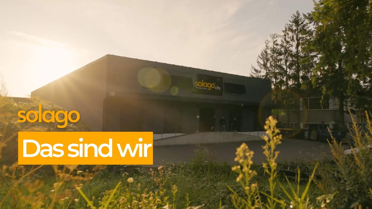 Video laden: Gebäude mit &#39;solago city&#39; Schild bei Sonnenaufgang und dem Text &#39;solago Das sind wir&#39; im Vordergrund